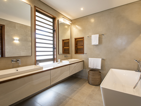 Salle de bain haut de gamme avec baignoire îlot et finitions naturelles dans une villa à Anahita