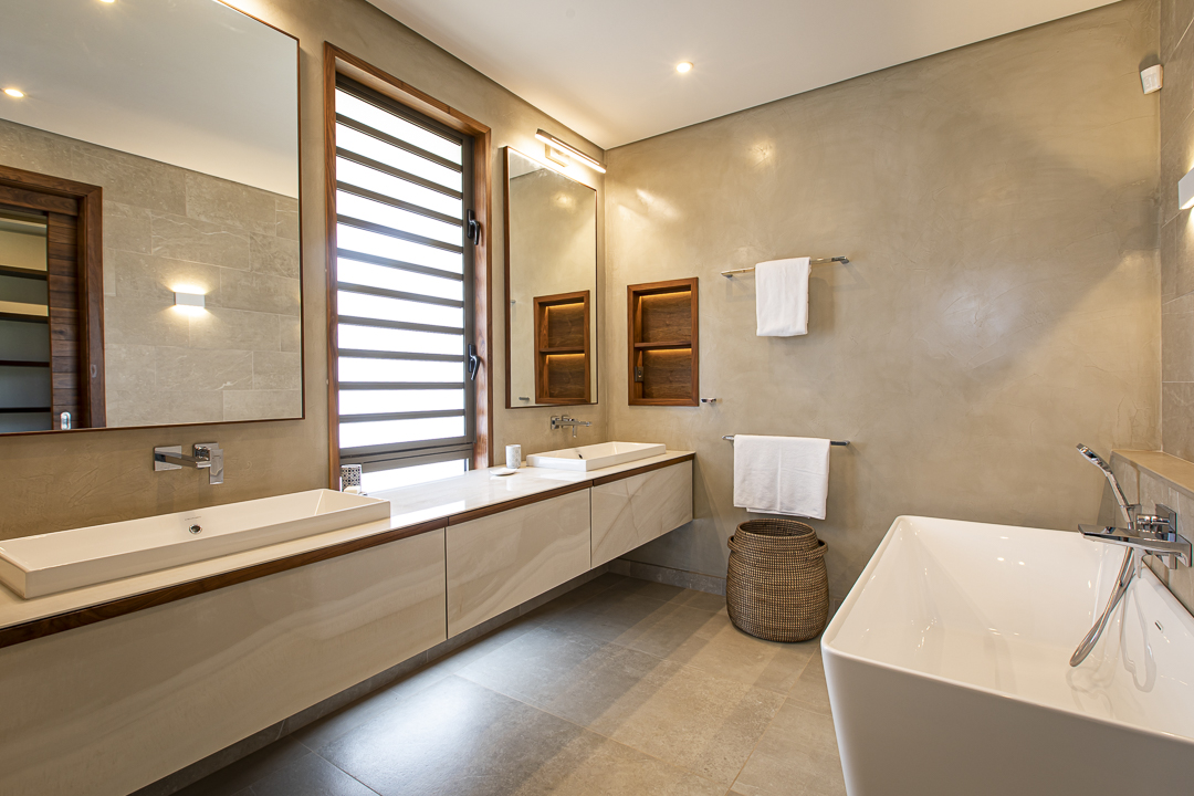 Salle de bain haut de gamme avec baignoire îlot et finitions naturelles dans une villa à Anahita